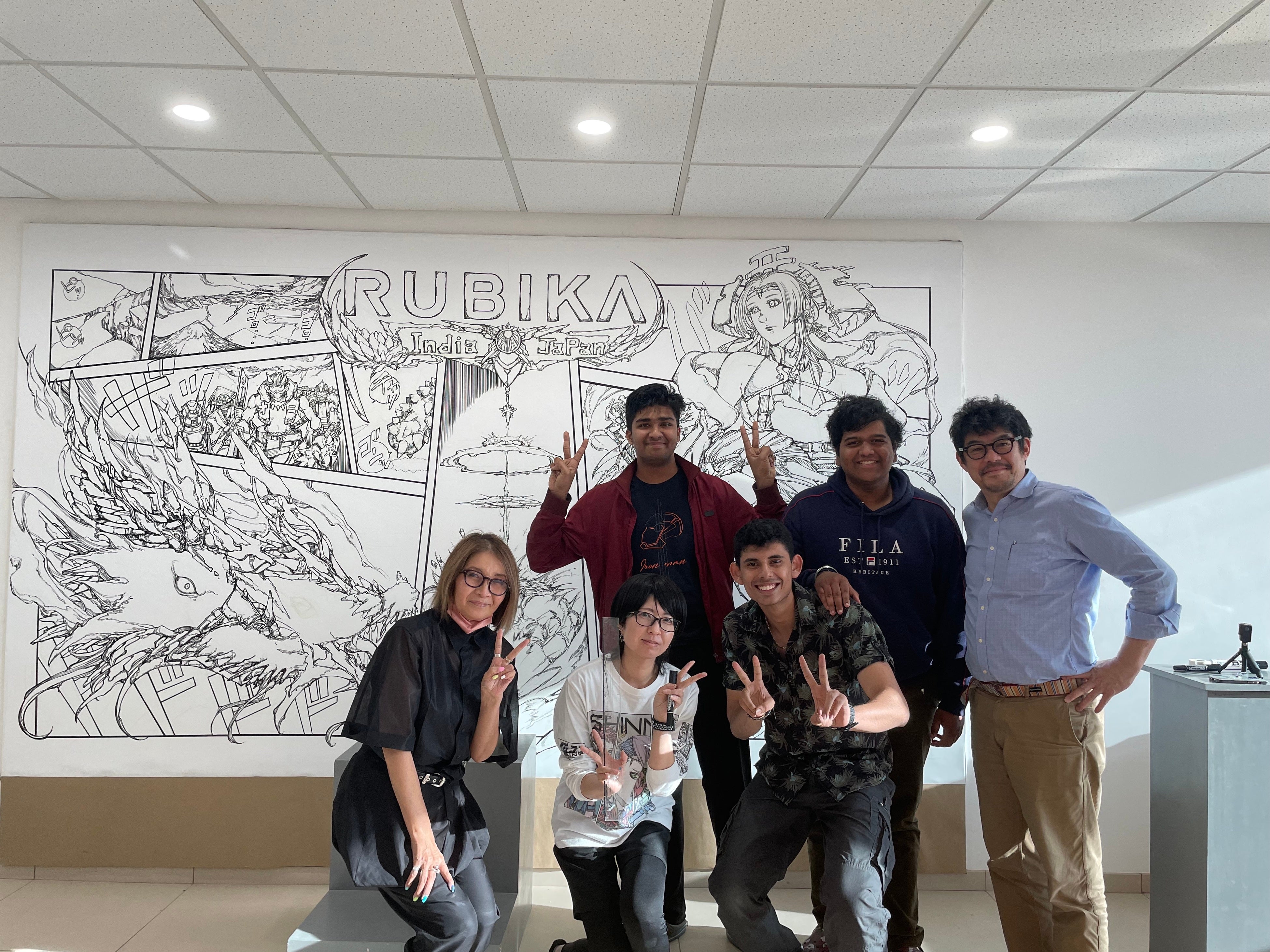 制作中のマンガを背景に生徒と記念撮影
