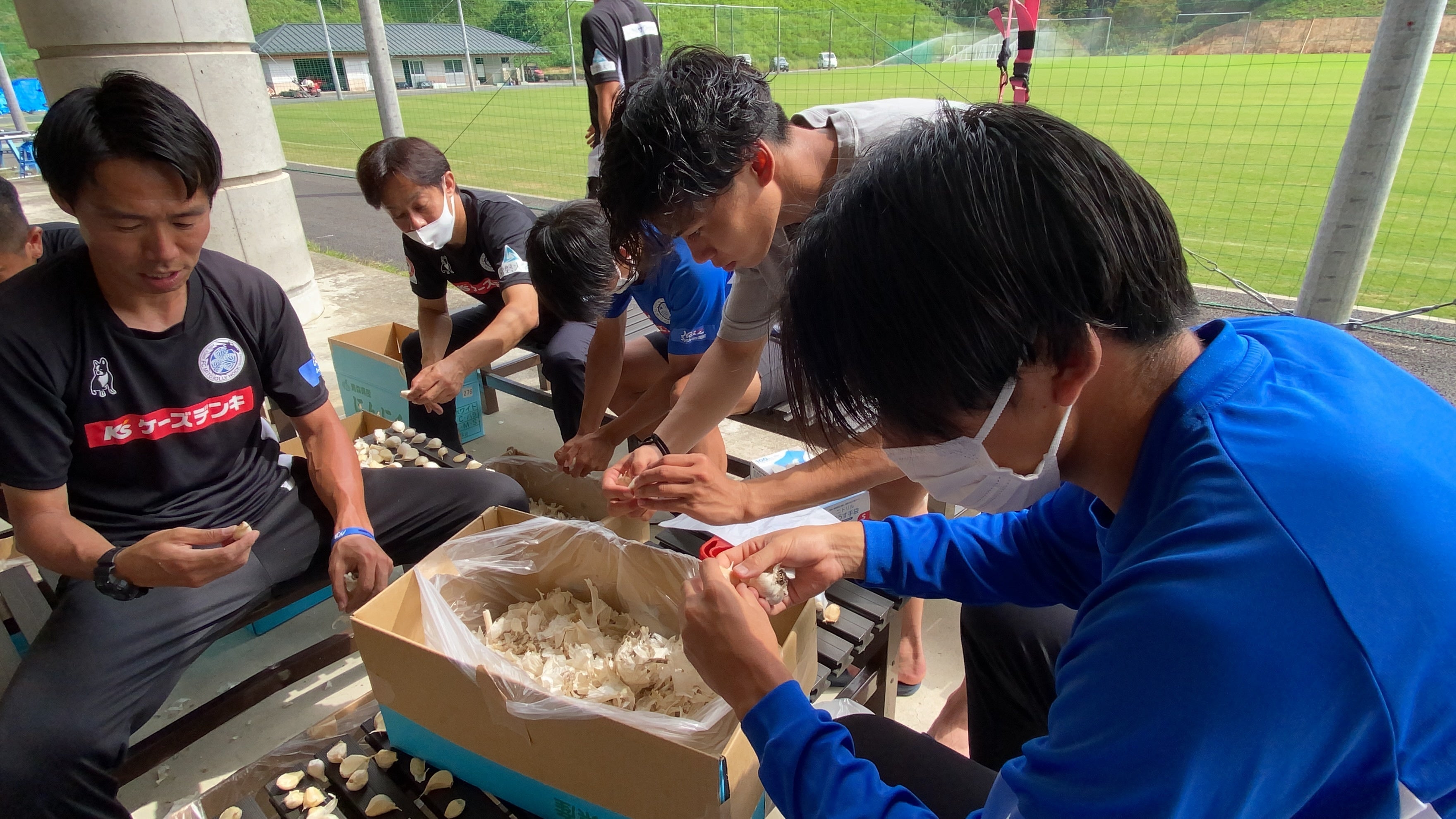 選手とともにニンニクの皮むきをしている様子