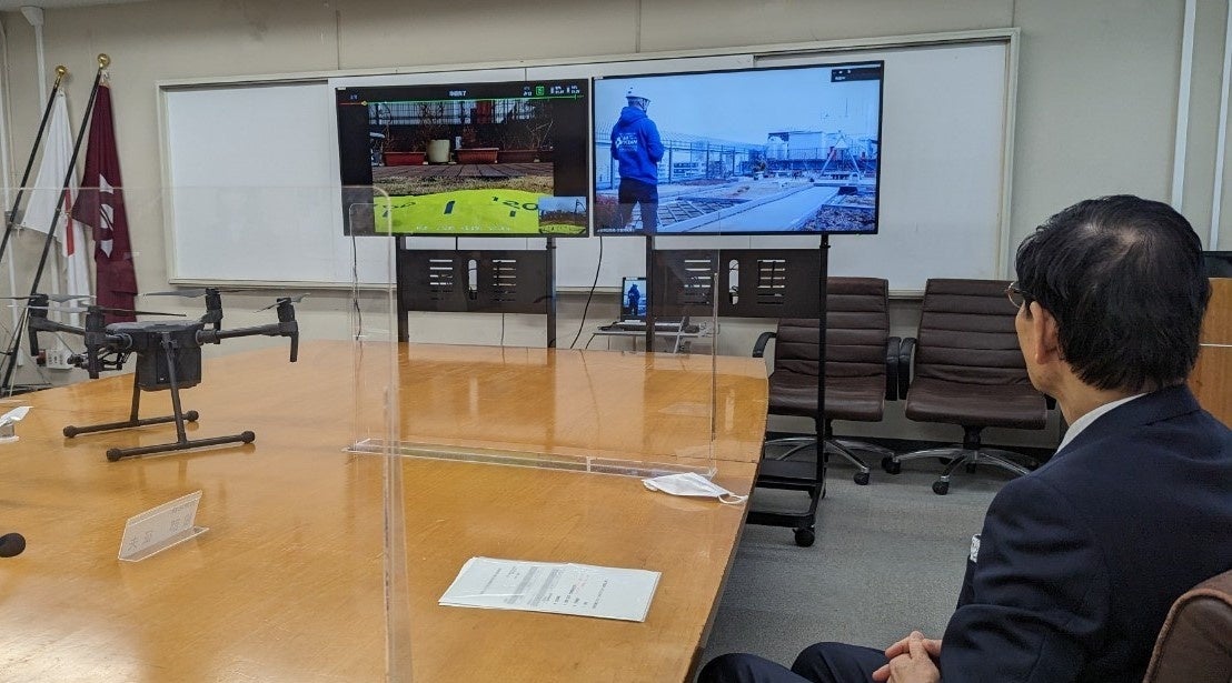 庁舎屋上からのフライトを調印式式場で確認(服部区長)