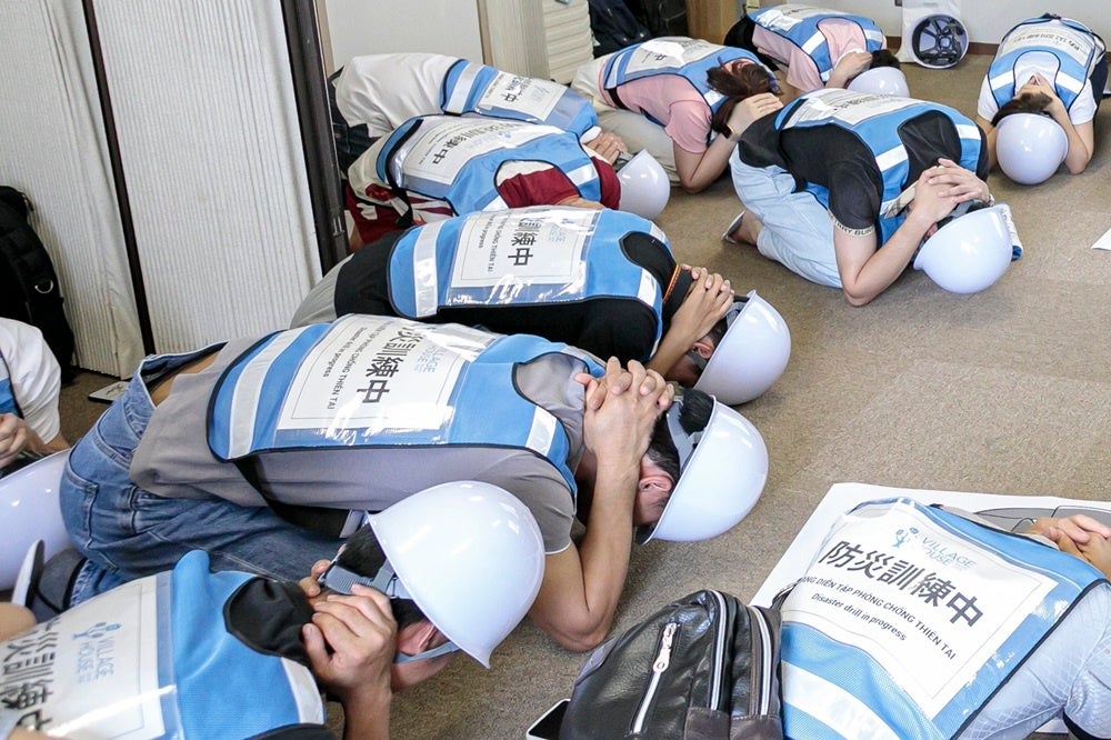 「シェイクアウト訓練」で首を手で守る動作を実践