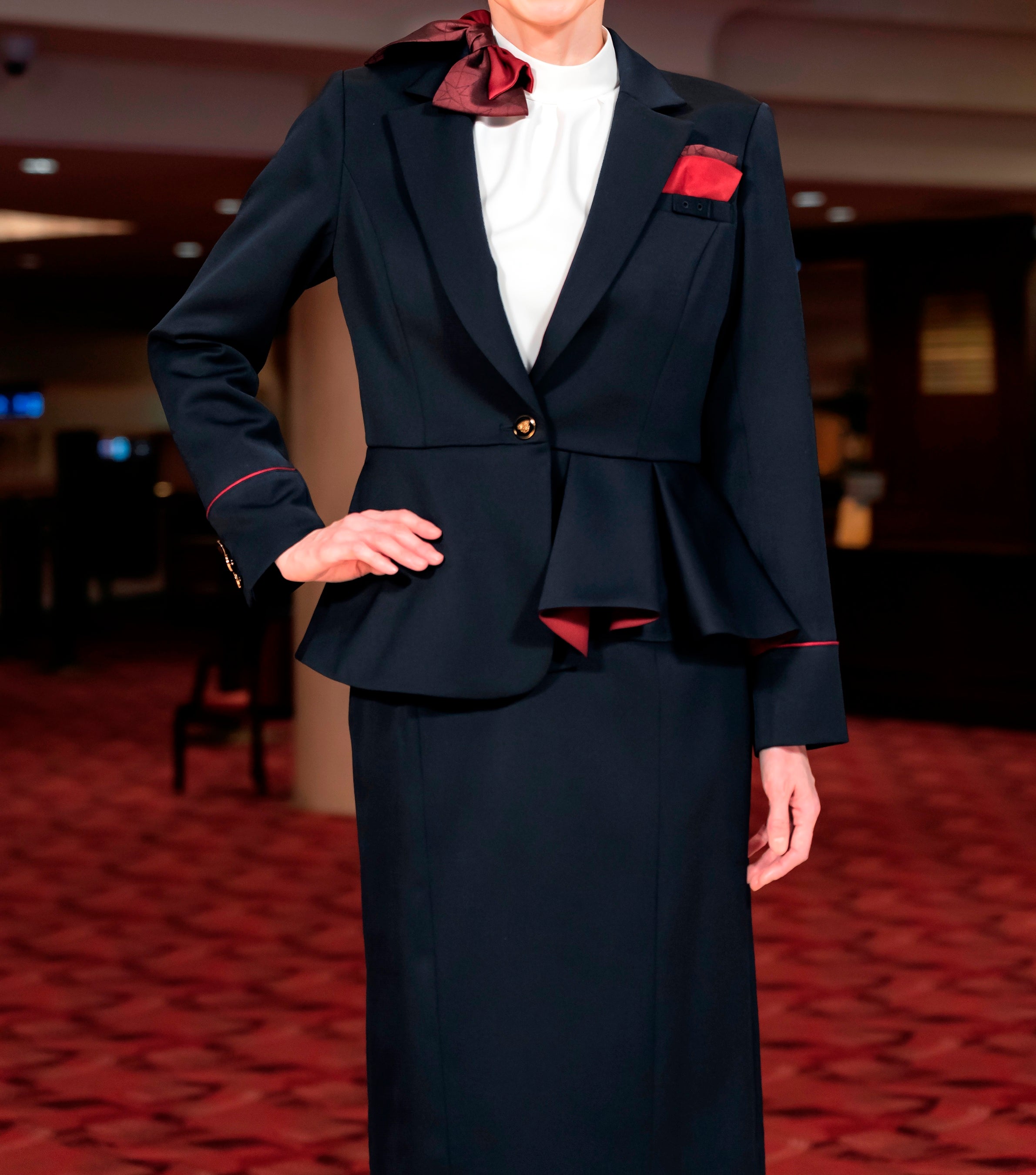 女性のジャケットは華やかで機能的なプリーツとサントリーホールのイメージカラーのワインレッドをアクセントに