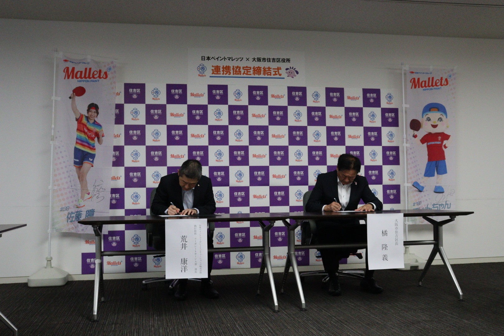 協定書にサインする両者