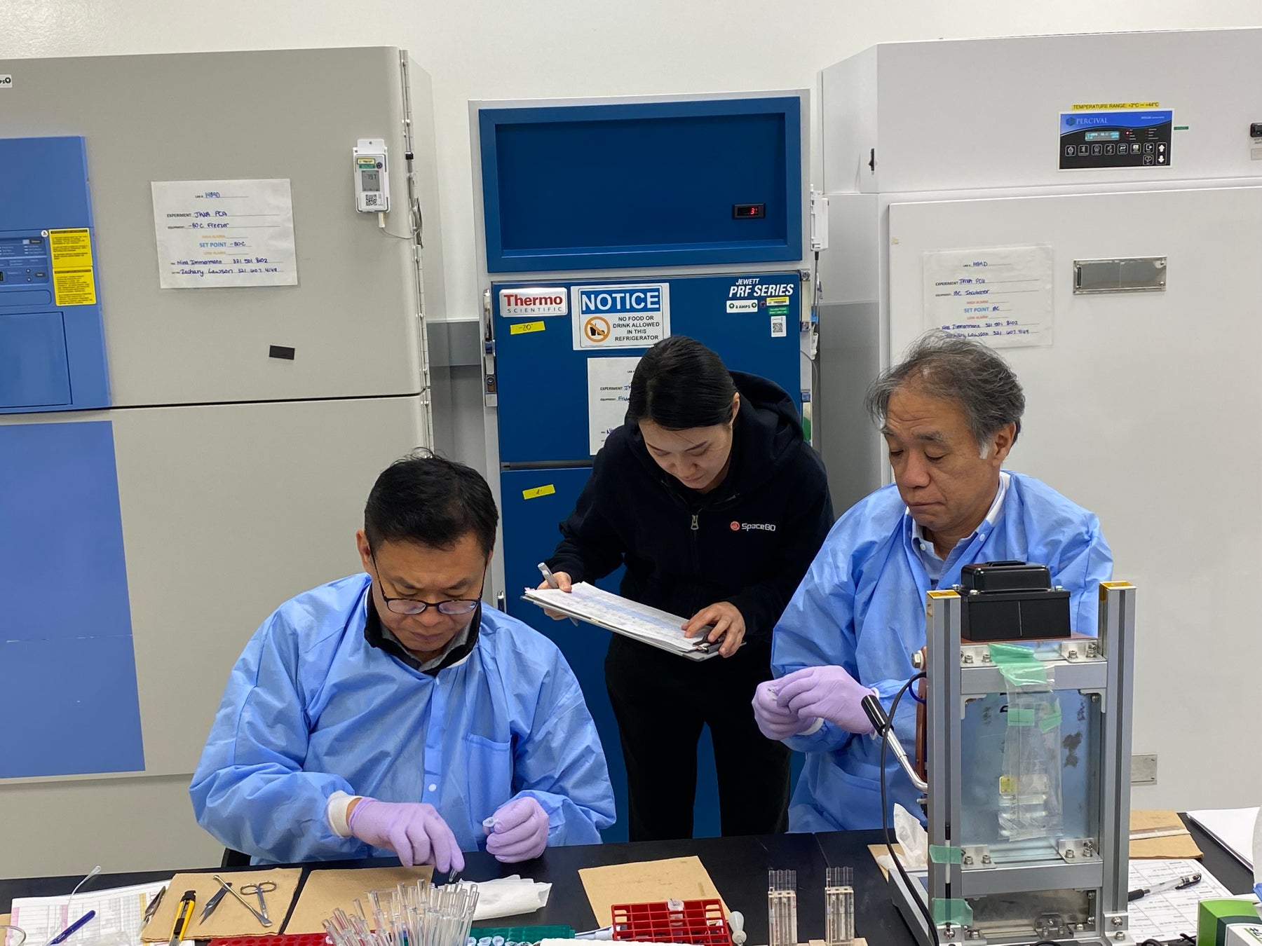 NASAケネディスペースセンターにてSpX-29搭載サンプルの充填作業をする様子(奥:Space BD社員)