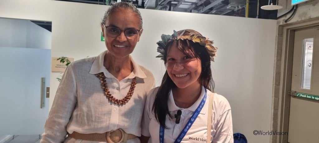 ブラジルのマリーナ・シルバ環境・気候変動大臣（左）とCOP28へのワールド・ビジョン代表団の一員であるブラジルのタイサちゃん（13歳）（右）。タイサちゃんはお母さんお手製のアサイーの実でつくったネックレスを大臣に手渡し、熱帯雨林保全の大切さを訴えました