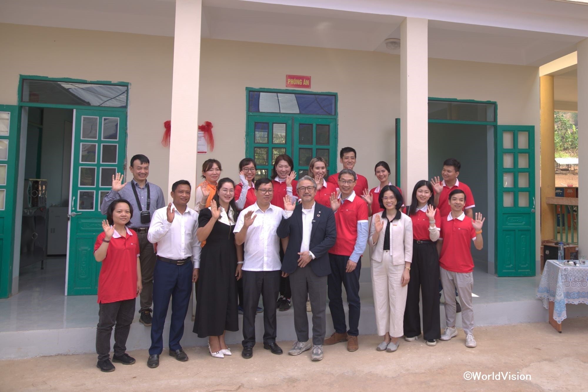 完成した給食調理施設の前で。森永乳業株式会社　取締役 常務執行役員 海外事業本部長 柳田氏（前列右から5人目） コミューン人民委員会委員長ロー氏（前列右から6人目）他