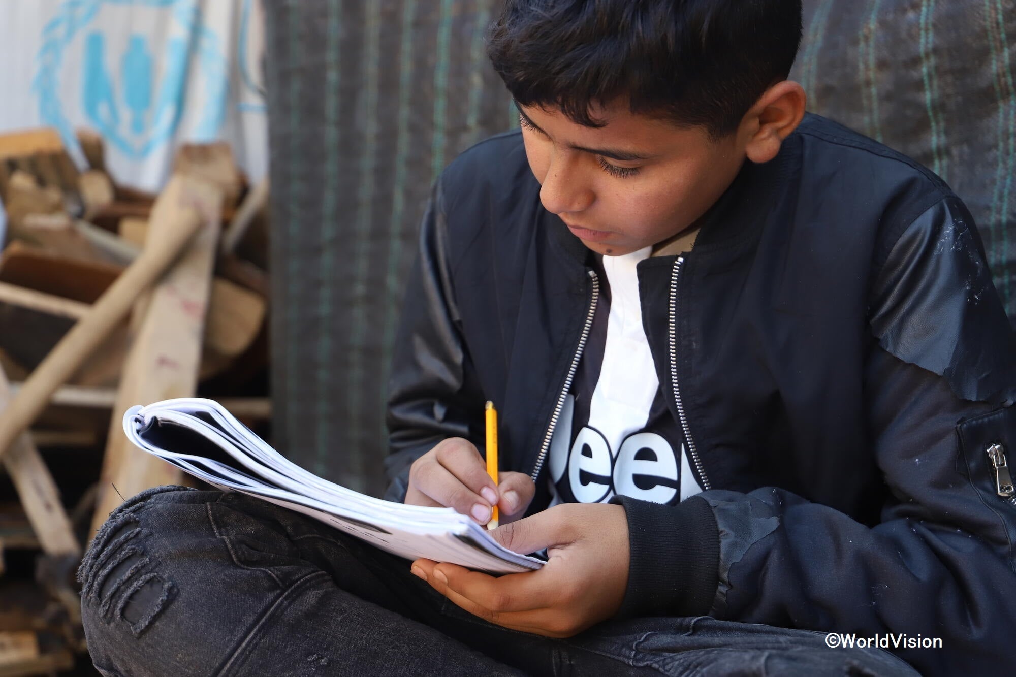 ノートを見返すシリア難民の男の子（レバノンの難民キャンプ）