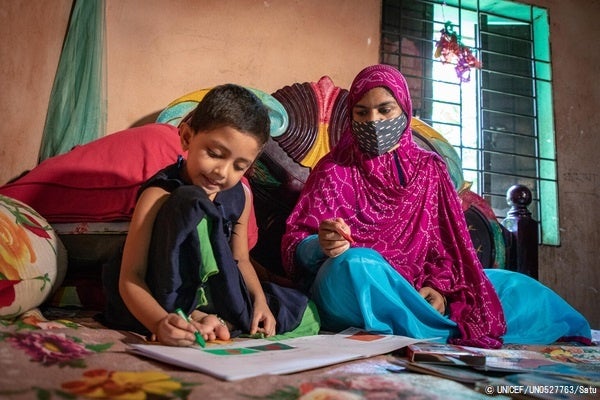 COVID-19の影響で未就学児向けの施設が一時的に閉鎖されたため、自宅を訪れたボランティアに教わりながら学習をすすめる4歳のスマイヤちゃん。(バングラデシュ、2021年8月撮影) © UNICEF_UN0527763_Satu