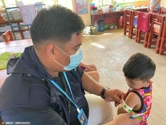 台風22号の被災直後、緊急で子どもの栄養検診を行った。上腕計測目メジャーで栄養状態のチェックを受ける子ども(2021年12月19日撮影) © UNICEF_UN0568609_