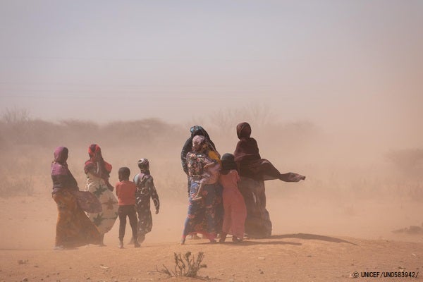 深刻な干ばつの被害を受けているソマリ地域の村で、砂埃が舞う中歩く人たち。(ソマリア、2022年1月撮影)　© UNICEF_UN0583942_