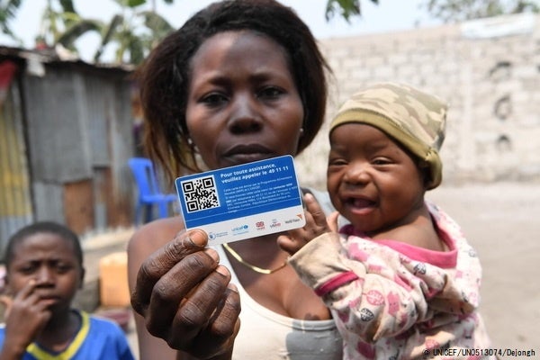 現金給付支援を受けられるカードを持つ、キンシャサの農村部に住む親子。COVID-19による経済的な影響で、子どもの食料確保が困難な家庭を対象に、現金給付支援が行われた。(コンゴ民主共和国、2021年8月撮影) © UNICEF_UN0513074_Dejo