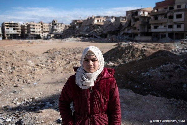 ダマスカスにて、紛争により破壊された街を背景に立つ11歳のアーミナさん。家族が働く建物が爆撃され父と兄を亡くした経験がトラウマとなり、突然の物音や動きが怖くなった。(シリア、2022年2月10日撮影) © UNICEF_UN0603129_Belal