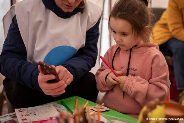 モルドバのパランカ国境近くの難民受け入れセンターにある、ユニセフとUNHCRのブルードットで、カウンセラーと遊ぶ4歳のダーシャちゃん。(モルドバ、2022年3月16日撮影) © UNICEF_UN0609220_Modola