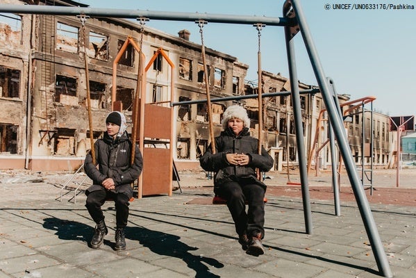砲撃によって破壊されたハルキウの学校で、ブランコにのる男の子たち。今年2月に紛争が激化して以来、ウクライナ全体で何百もの学校が被害を受けている。(ウクライナ、2022年3月18日撮影)© UNICEF_UN0633176_Pashkina