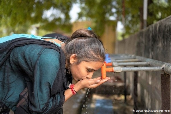 学校に設置している水飲み場で、水を飲む15歳のドゥルガーさん。住んでいる村の学校できれいな水とトイレが使えるので、この校舎で勉強できることを喜んでいる。(インド、2022年1月撮影) © UNICEF_UN0652690_Panjwani