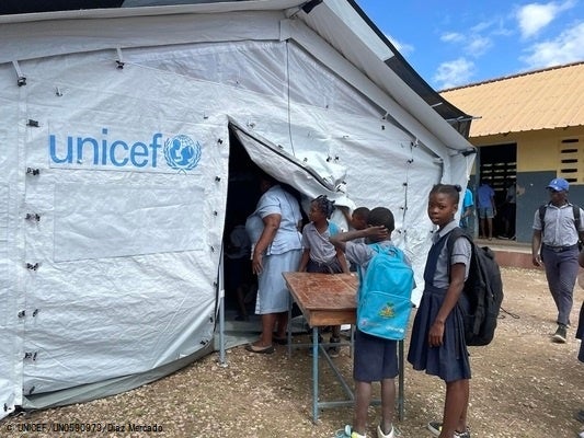 ユニセフの仮設テントの中に机を運ぶ子どもたち。(ハイチ、2022年2月撮影) © UNICEF_UN0590979_Diaz Mercado