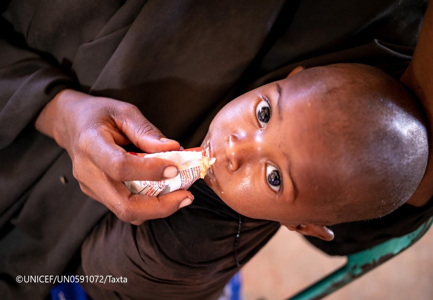 ドロー避難民キャンプ内にある保健センターで、ユニセフ支援物資の栄養補助食を食べる幼い子ども。（ソマリア、2022年2月3日撮影）©UNICEF_UN0591072_Taxta