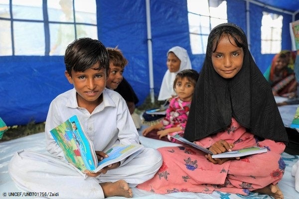 シンド州の国内避難民キャンプの中にあるユニセフが支援する仮設学習センターで、授業を受ける8歳のパルベーズさん(左)と12歳のサムリーンさん(右)姉弟。(パキスタン、2022年9月5日撮影)© UNICEF_UN0701756_Zaidi
