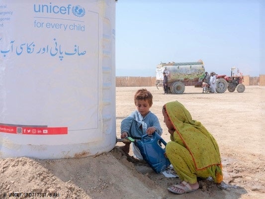 バロチスタン州から37世帯が避難した一時避難所で、ユニセフが支援した給水タンクからきれいな水を汲む子どもたち。(パキスタン、2022年9月15日撮影) © UNICEF_UN0717381_dAki