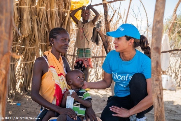 栄養不良の診察を受け、すぐ食べられる栄養治療食(RUTF)を受け取った2歳のアポロちゃんと、寄り添うプリヤンカー・チョープラー・ジョナス親善大使。(ケニア、2022年10月18日撮影) © UNICEF_UN0722082_Wahome