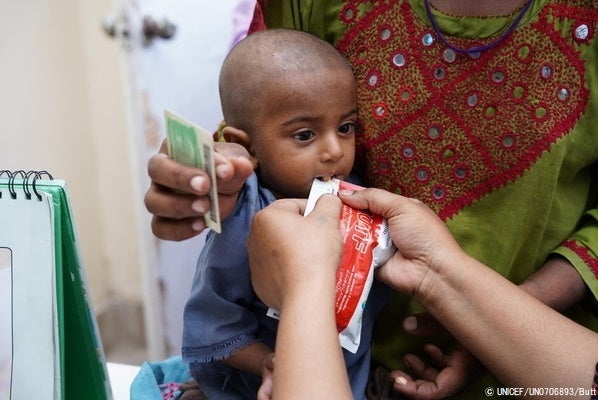 シンド州にある洪水の被害に遭った子どもたちのためのユニセフの栄養キャンプで、すぐに食べられる栄養治療食(RUTF)を口にする1歳のジャハンギルちゃん。(パキスタン、2022年9月14日撮影) © UNICEF_UN0706893_Butt