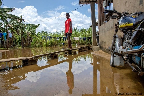 バイエルサ州で、浸水した自宅の前に作った仮設通路を使う11歳の男の子。(ナイジェリア、2022年10月4日撮影) © UNICEF_UN0722938_Esiebo