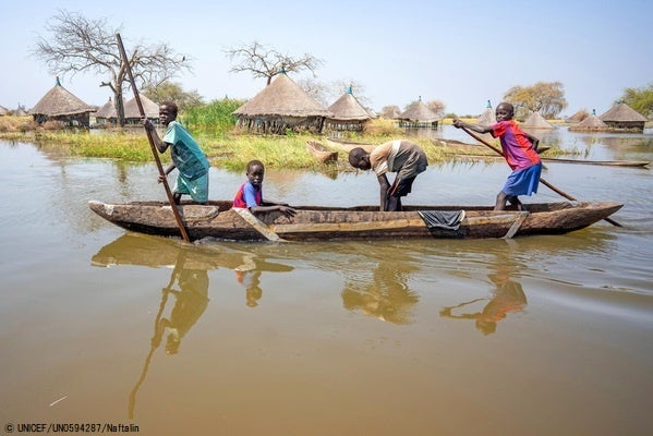 ジョングレイ州で、洪水により浸水した村の中をカヌーに乗り移動する子どもたち。(南スーダン、2022年1月撮影) © UNICEF_UN0594287_Naftalin