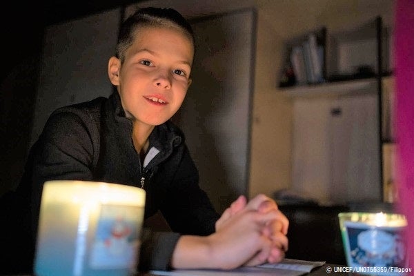 ブチャで、キャンドルの明かりを使って宿題をする11歳のティモフェイさん。日中は空襲のサイレンが鳴り、学校の授業が中断されることも多い。(ウクライナ、2022年11月撮影) © UNICEF_UN0755359_Filippov
