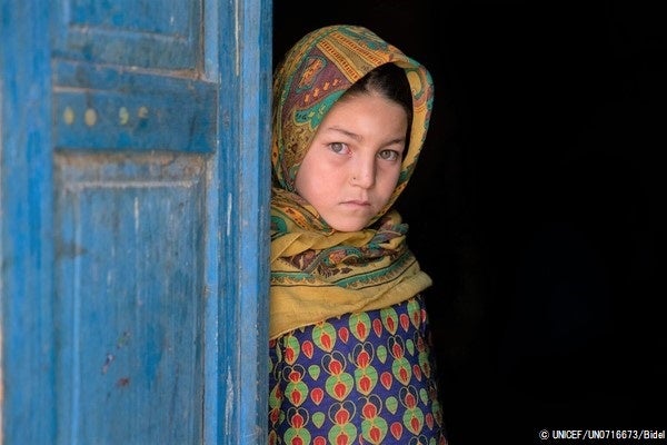 自宅のドアの前に立つ9歳のアスナさん。父親の稼ぎだけでは足りなく、現金給付支援を2回受け、米、小麦粉、油や必要な食料品を買うことができた。(アフガニスタン、2022年10月撮影) © UNICEF_UN0716673_Bidel