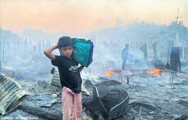 焼け野原となった難民キャンプから荷物を運ぶ男の子。(バングラデシュ、2023年3月5日撮影) © UNICEF_UN0796340_Lateef