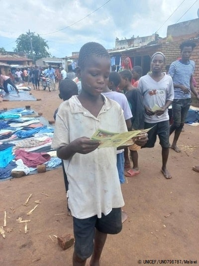 マチンガ県で配布されたコレラについてのチラシを読む男の子。(マラウイ、2023年3月5日撮影) © UNICEF_UN0796787_Malawi