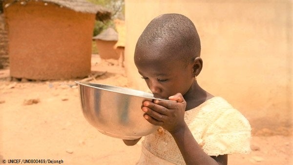 北部の村で、ユニセフの支援で設置された太陽光発電式の水道から汲んだ水を飲む子ども。(コートジボワール、2023年3月7日撮影) © UNICEF_UN0800469_Dejongh