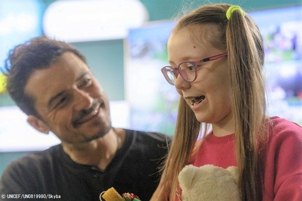 キーウの地下鉄構内にあるユニセフのスピルノ・チャイルド・スポットで、ろうそく作りをする8歳のミラーナさんと話すオーランド・ブルーム ユニセフ親善大使。(ウクライナ、2023年3月25日撮影) © UNICEF_UN0819980_Skyba