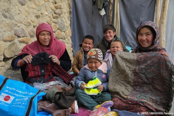 日本からの支援で届けられた、ユニセフの冬服の支援物資を受け取った家族。長男の15歳のモハマドくん(右から3番目奥)は、父親が亡くなったため一家の大黒柱として牛飼いの仕事をしている。(アフガニスタン、2023年2月撮影) © UNICEF_UN0804996