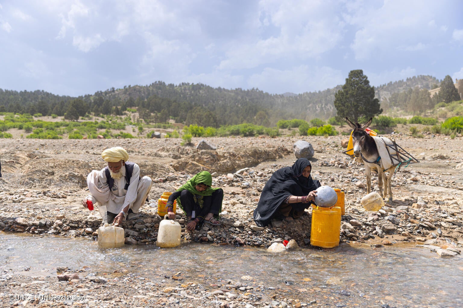 ホースト州の村に流れている川に、祖父母と一緒にロバを連れて水を汲みに行く6歳のヌーバラさん。夏は炎天下になる中、毎日2時間かけて水を汲みに行っている。(アフガニスタン、2023年6月撮影) © UNICEF_UNI399211_Bidel