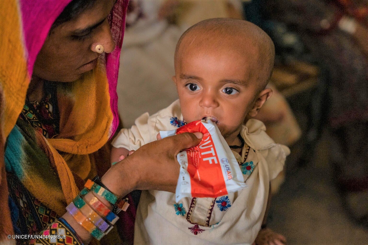 すぐに食べられる栄養治療食(RUTF)を母親に食べさせてもらう重度の急性栄養不良の1歳のラシードちゃん。(パキスタン、2023年6月撮影) © UNICEF_UNI404698_Butt