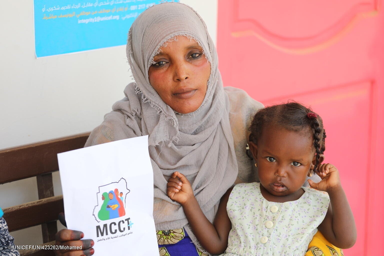 ポートスーダンの保健施設にある現金給付センターで、子どものいる家庭が四半期ごとに現金を受け取ることができる、ユニセフの現金給付プログラムに登録した親子。(スーダン、2023年7月撮影) © UNICEF_UNI423262_Mohamed