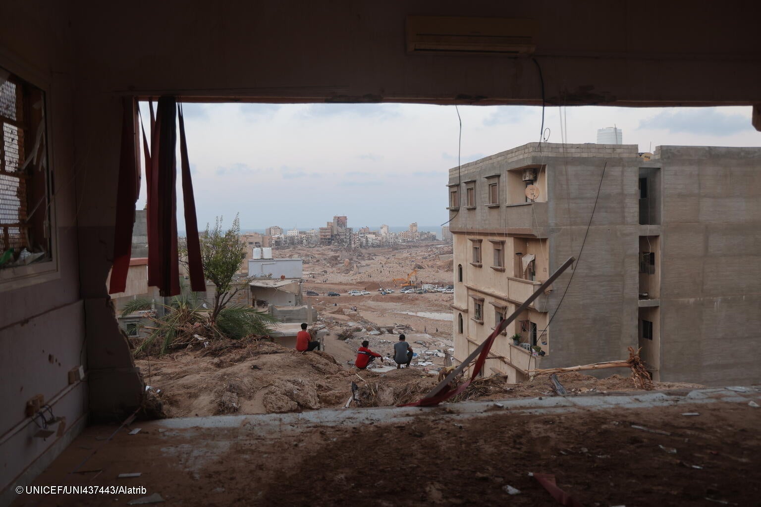 デルナで洪水により被災したアパートの前に集まる人たち。(リビア、2023年9月16日撮影) © UNICEF_UNI437443_Alatrib