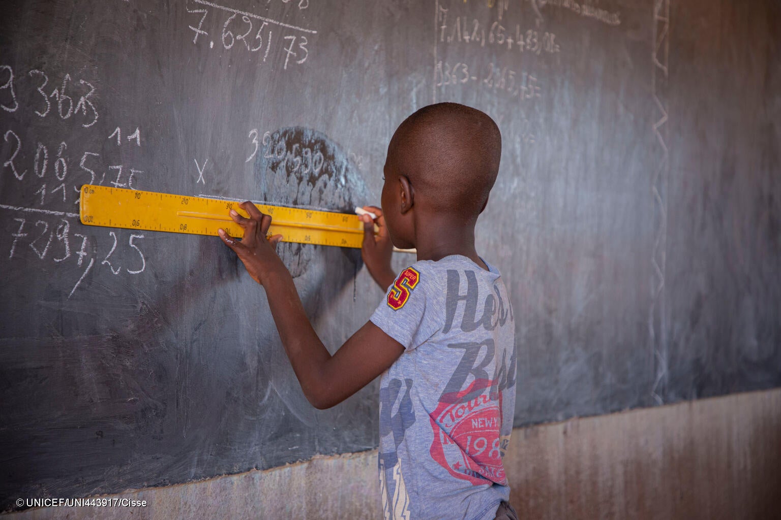 中北部地方のカヤの公立学校で、定規を使って黒板に計算式を書き込む子ども。(ブルキナファソ、2023年9月27日撮影) © UNICEF_UNI443917_Cisse