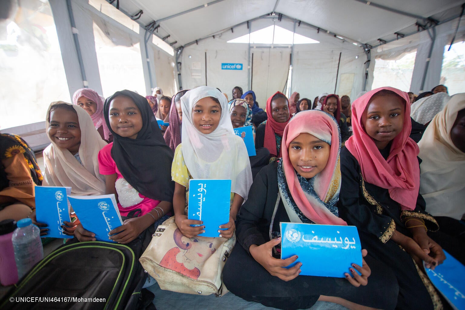 ジャジーラ州のユニセフが設置した安全な学習空間で、ノートや鉛筆、スクールバッグなどの支援物資を受け取り、授業に参加する国内避難民の子どもたち。(スーダン、2023年10月7日撮影) © UNICEF_UNI464167_Mohamdeen