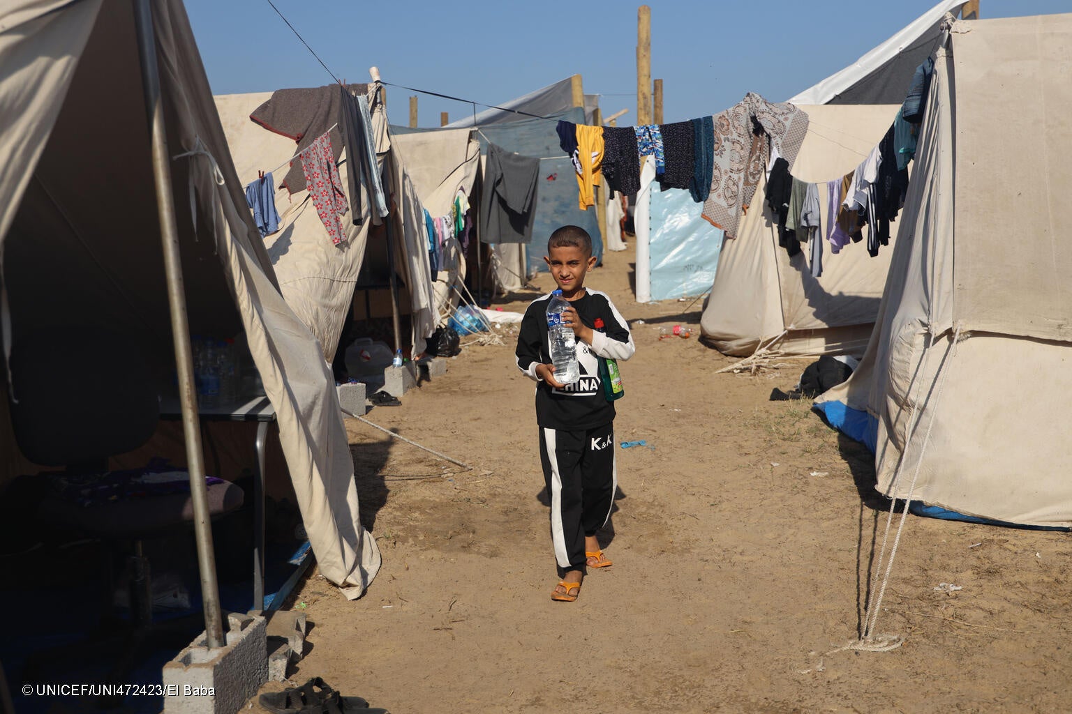 ガザ地区の北部から南部の避難民キャンプへ逃れ、ユニセフが支援する水ボトルを受け取った9歳のマジュドさん。「戦争が終わってほしい。食料と水が足りない」と話す。(ガザ地区、2023年11月15日撮影) © UNICEF_UNI472423_El Baba