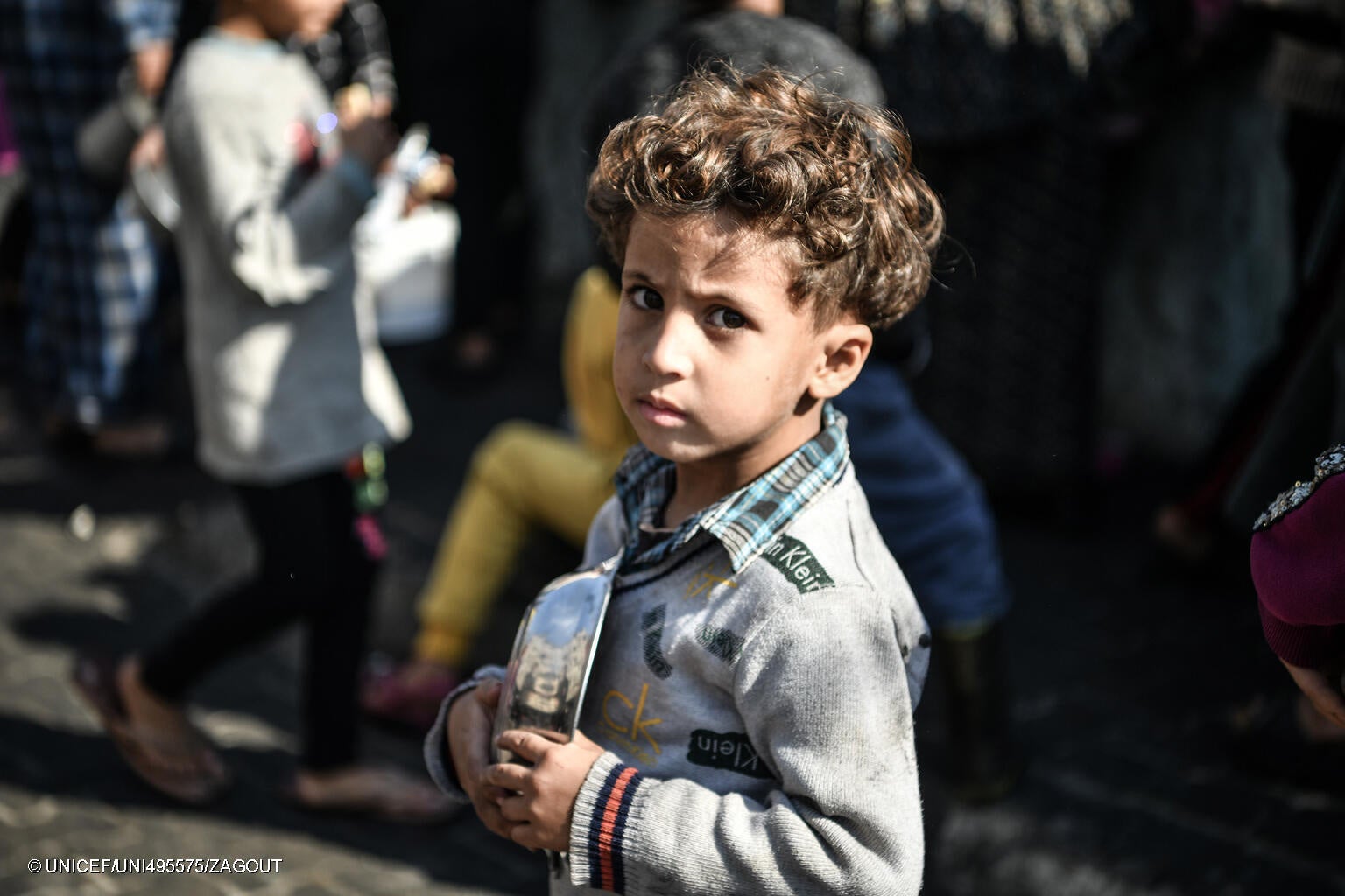 炊き出しを受け取るための順番待ちをする5歳のアフマドちゃん。「お腹が空いている。ご飯を受け取りたくて、ここでずっと待っているんだ」と話す。(ガザ地区、2023年12月19日撮影) © UNICEF_UNI495575_ZAGOUT