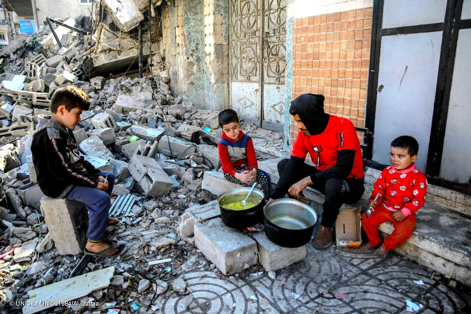 破壊された自宅前で、焚火で料理を作る家族。(ガザ地区、2024年1月11日撮影) © UNICEF_UNI501984_Al-Qattaa