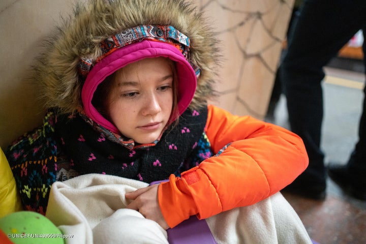 キーウの地下鉄のホームに座り込む14歳のオレクサンドラさん。3日前に爆撃を受けた隣の家の破片が自宅に直撃し、危険を感じた一家はシェルターに避難した。(ウクライナ、2024年1月2日撮影) © UNICEF_UNI498556_Filippov