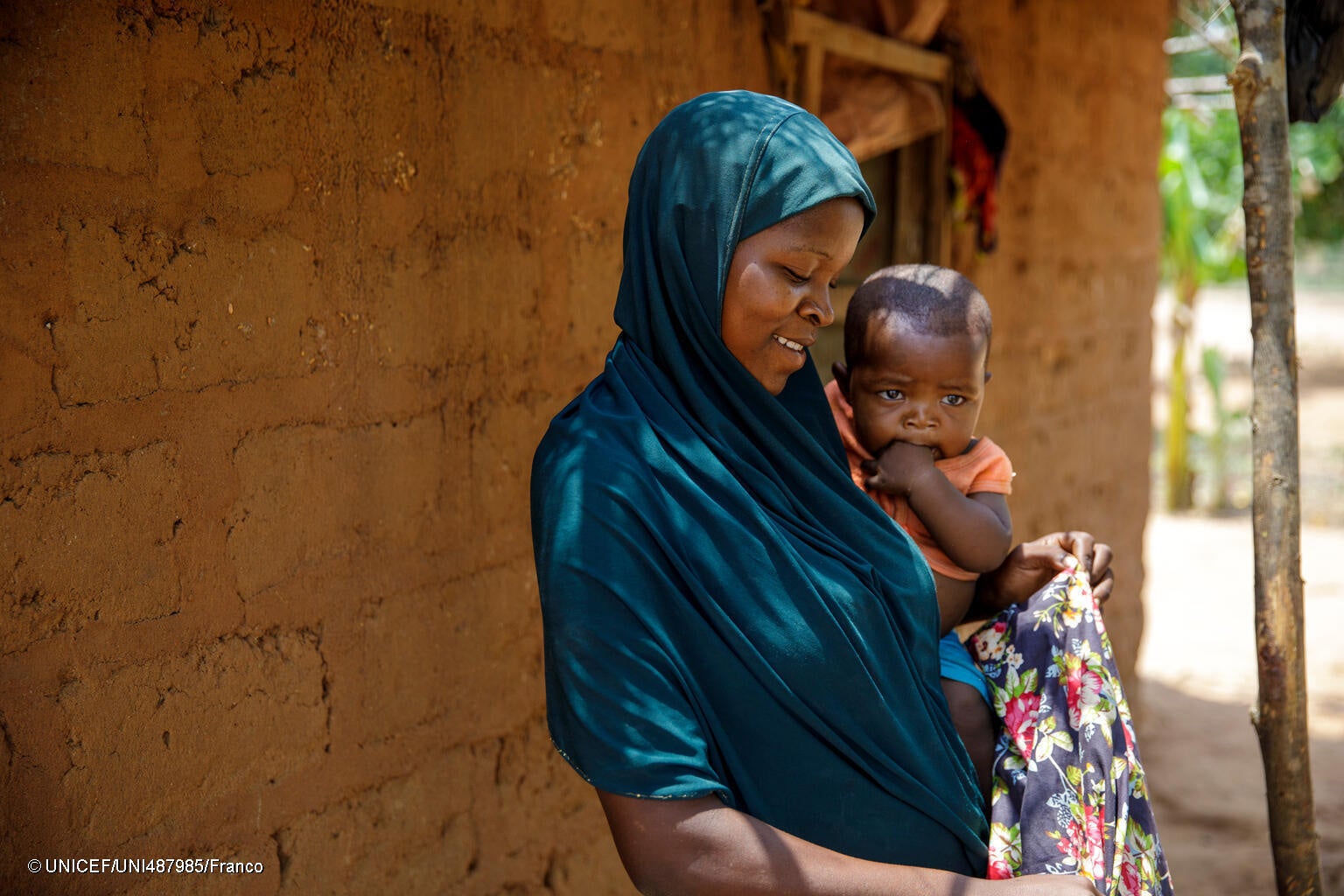 2歳未満の子どもがいる家庭を対象にしたユニセフによる現金給付を受け取った、ひとり親の母親と生後6カ月の子ども。家族のためにキャッサバや小麦粉、砂糖などを購入すると話す。(モザンビーク、2023年12月撮影) © UNICEF_UNI487985_Franc