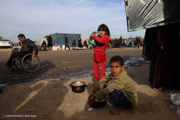 避難所のテントの近くで、家族と食べ物を探す子どもたち。(ガザ地区、2024年1月31日撮影) © UNICEF_UNI521740_El Baba