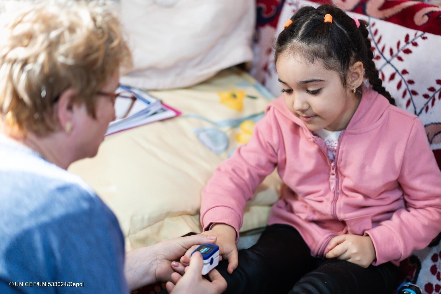 自宅を訪問する看護師に脈拍と酸素飽和度を計測してもらう5歳のアントニアちゃん。3歳のときに肺炎になったため合併症のリスクが高く、定期的な健診が必要。(ルーマニア、2024年2月28日撮影) © UNICEF_UNI533024_Cepoi