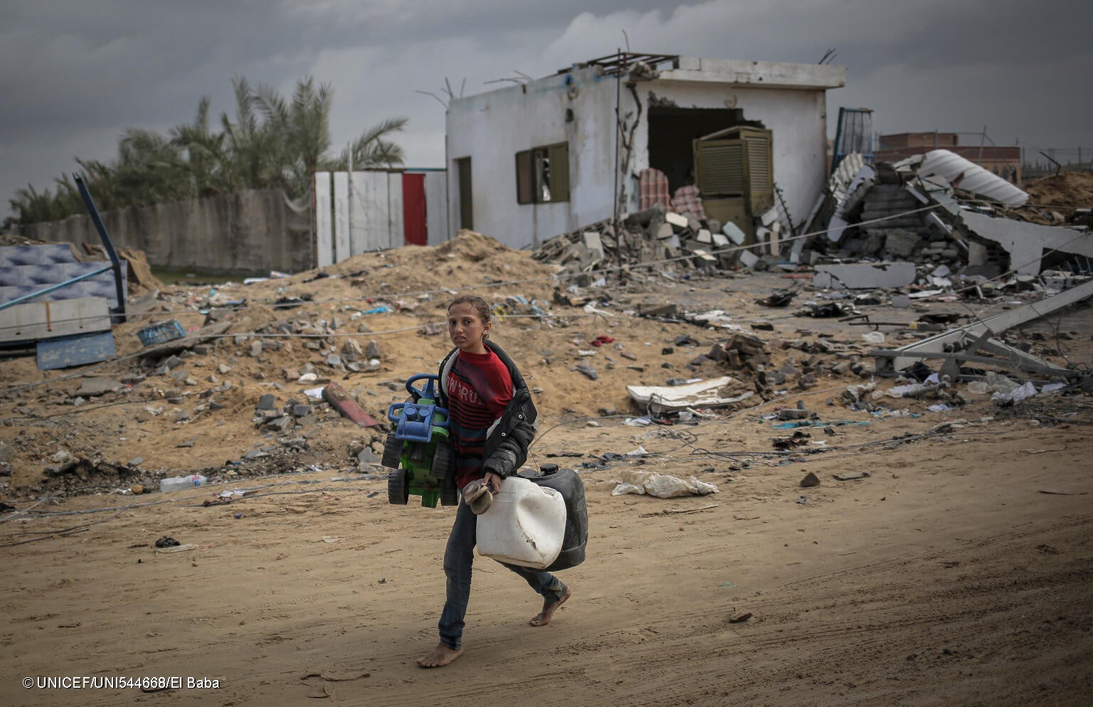 南部ハンユニスで、破壊された自宅跡のがれきから持ち物を運ぶ15歳のアスマさん。家財の多くが焼失する中、「弟のおもちゃの車だけは見つけられました」と話す。(ガザ地区、2024年3月22日撮影) © UNICEF_UNI544668_El Baba