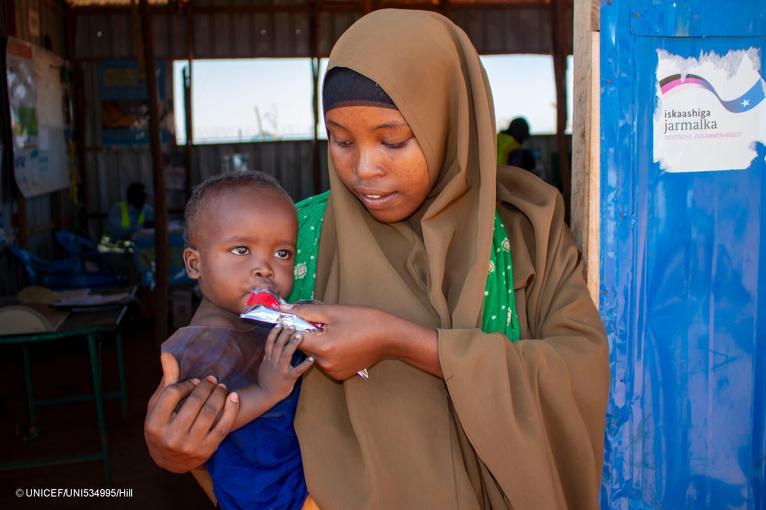 干ばつや洪水の被害を受け、国内避難民キャンプへ逃れた母親と生後7カ月のファヒアちゃん。重度の急性栄養不良のため、すぐに食べられる栄養治療食(RUTF)による治療を受けている。(ソマリア、2024年1月撮影) © UNICEF_UNI534995_Hill