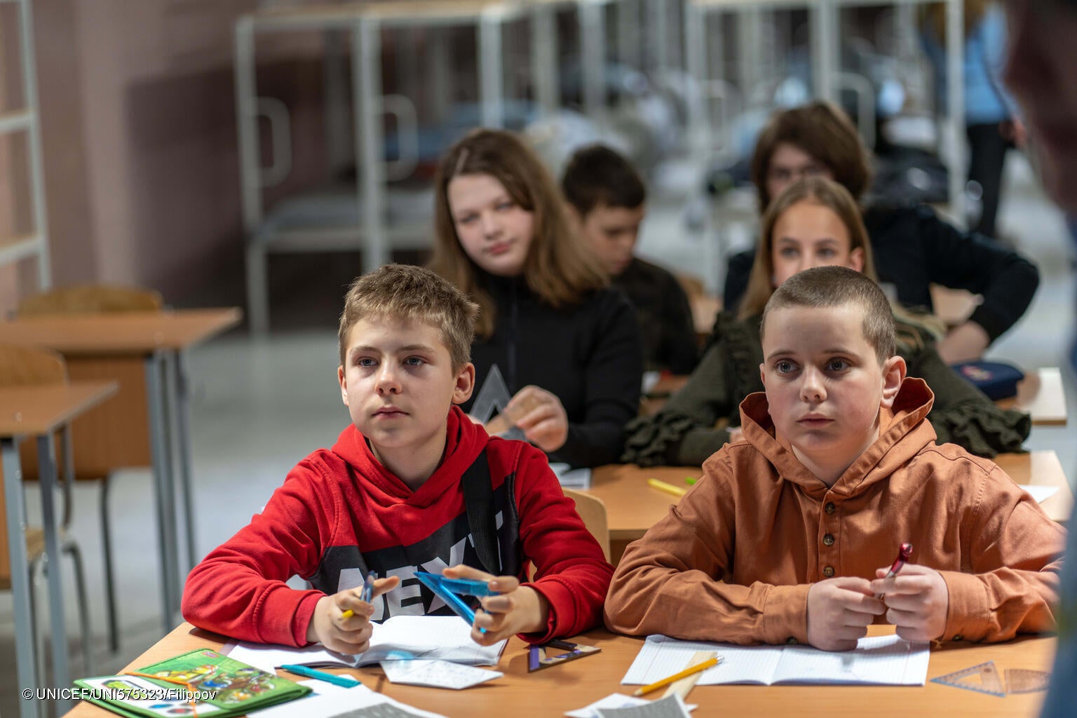ハルキウにある学校の地下シェルターで授業を受ける12歳のイホールさん(左)。「2年間、自宅でオンライン学習をしていた分を取り戻すために、勉強しています」と話す。(ウクライナ、2024年3月撮影) © UNICEF_UNI575323_Filippov