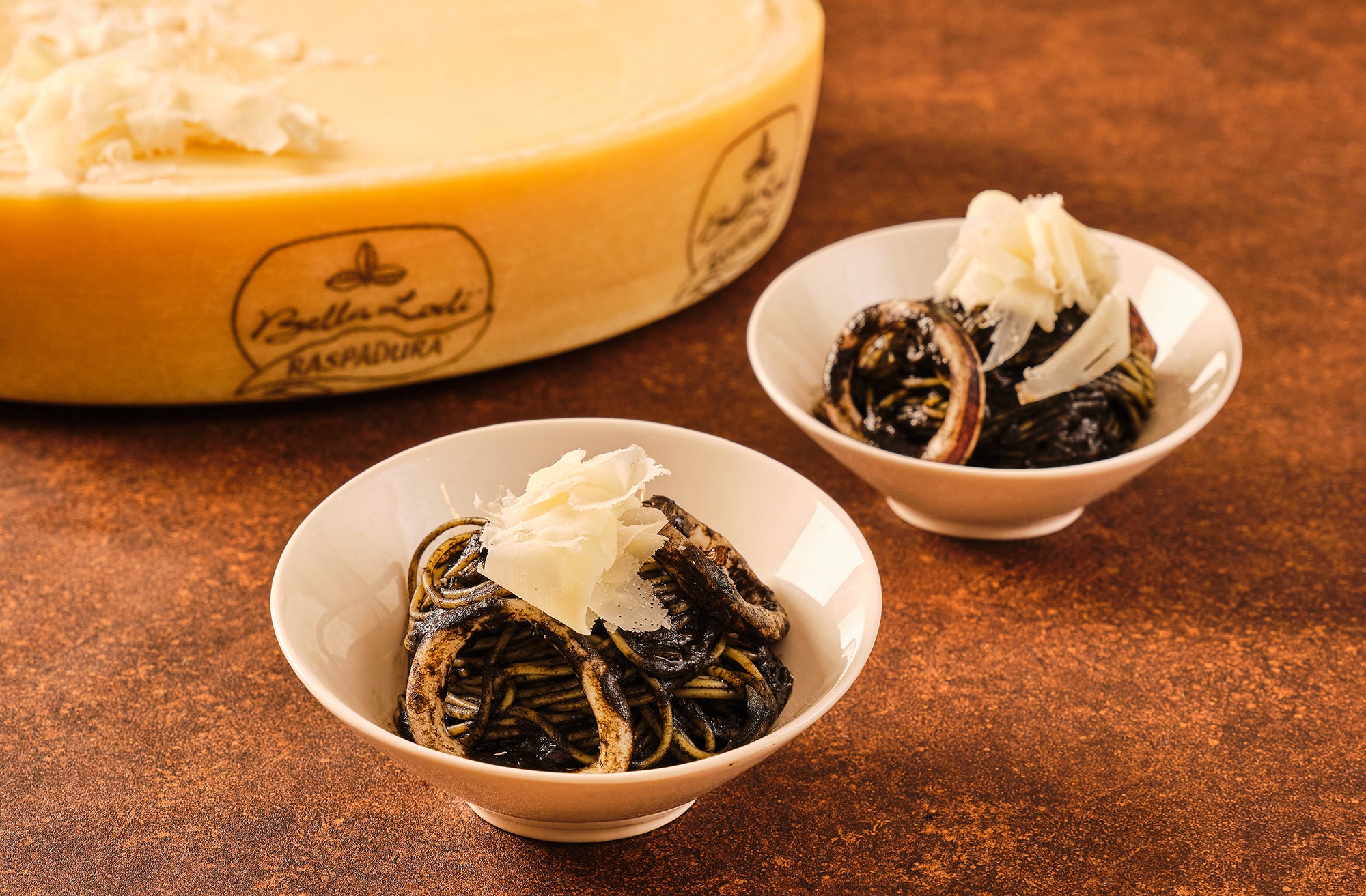 削り立てのふわふわのチーズを添えたイカ墨パスタ